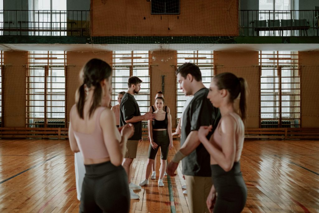 A group of people practicing and training in a gym setting, focusing on teamwork and coordination.