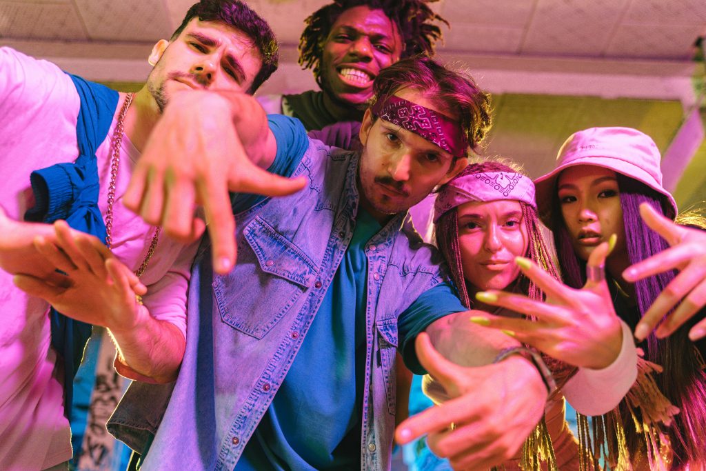 Vibrant group of diverse young adults having fun and dancing with neon lights indoors.